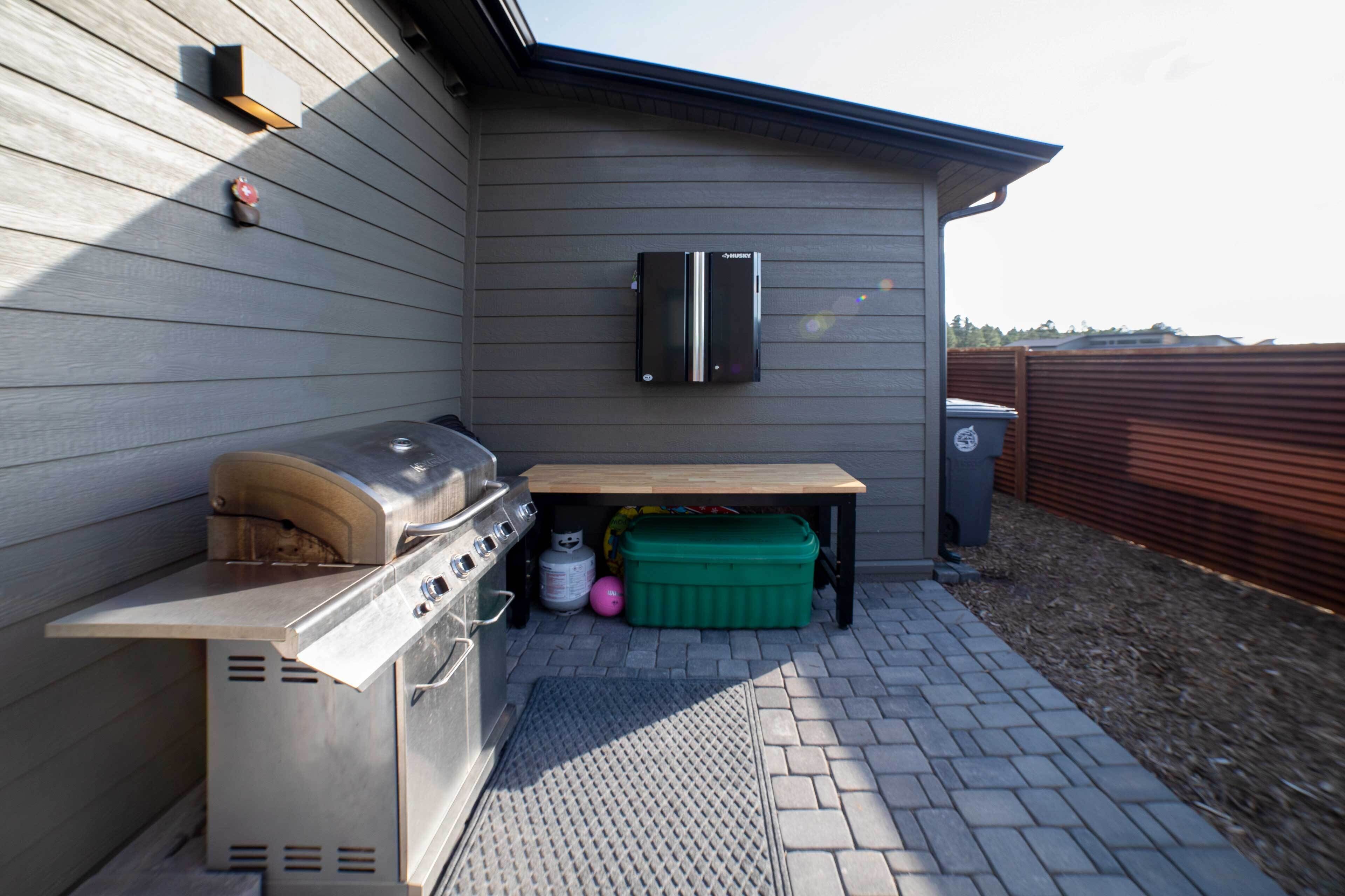 An outdoor kitchen area with a grill, a table, and a green cooler.