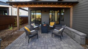 An outdoor patio with wicker furniture and a table, under a pergola with string lights. - Modern Flagstaff Escape w/ Grill, 3 Mi to Downtown (Flagstaff)