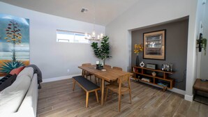 A modern living room with a wooden dining table, bench, and chairs. There is a sofa, a potted plant, and a bookshelf with decorative items. - Modern Flagstaff Escape w/ Grill, 3 Mi to Downtown (Flagstaff)