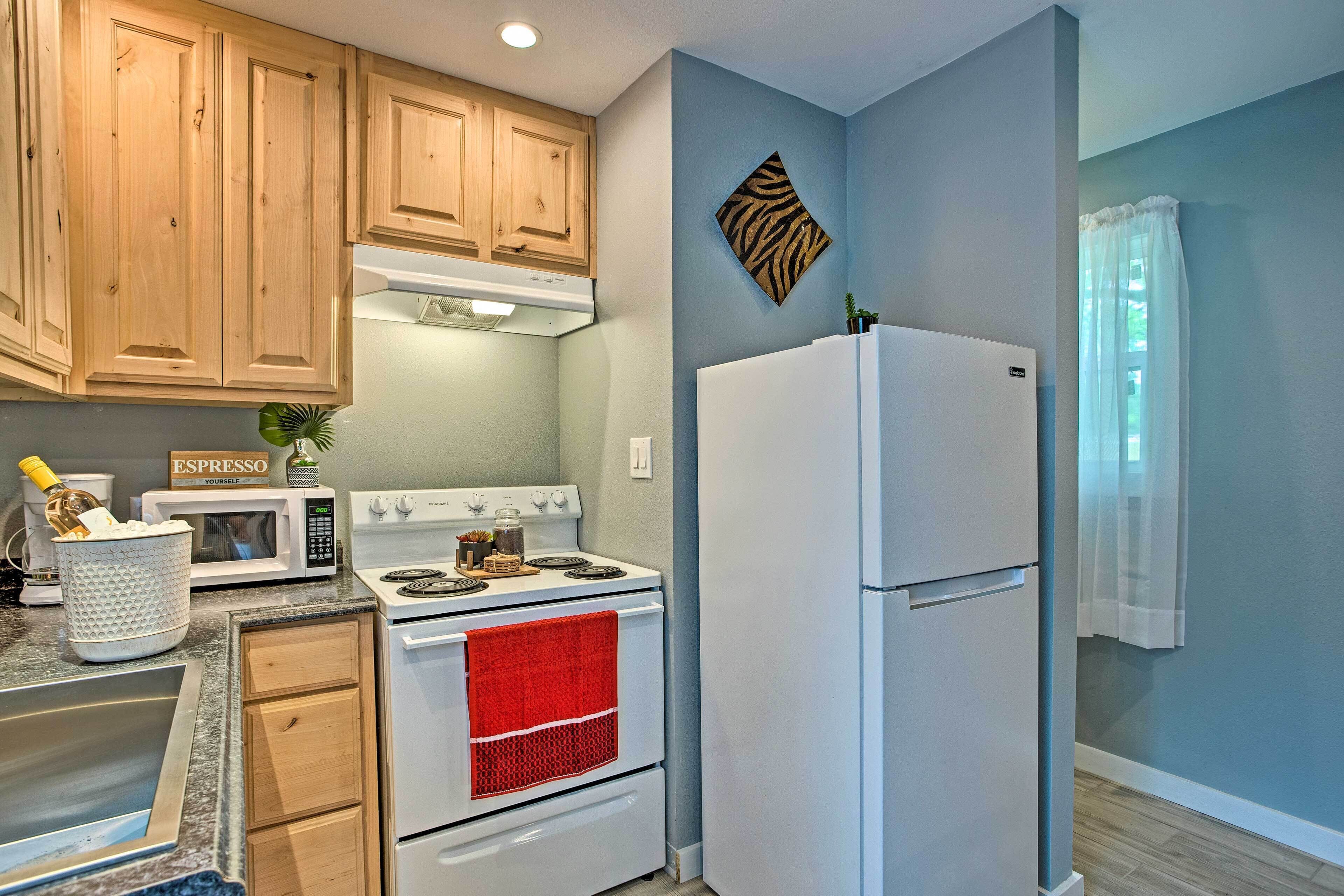 A kitchen with wooden cabinets, a white stove, a white refrigerator, and a red towel hanging on the oven door.