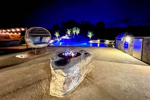 Ein Steinkamin mit Feuer, umgeben von einer Beton-Terrasse.