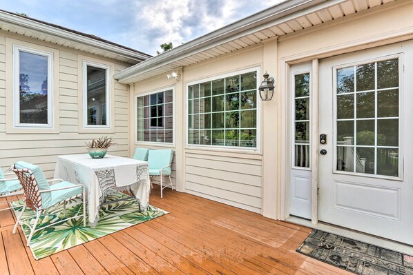 A covered patio with a table and chairs, a welcome mat, and a door with a window. - Charles Town Home w/ Private Pool & Hot Tub (Charles Town)