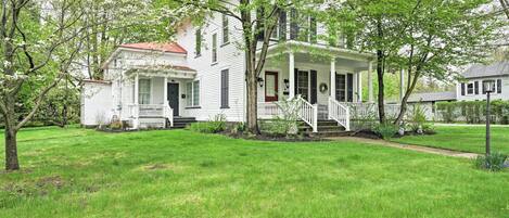 A white two-story house with a porch and a red roof.