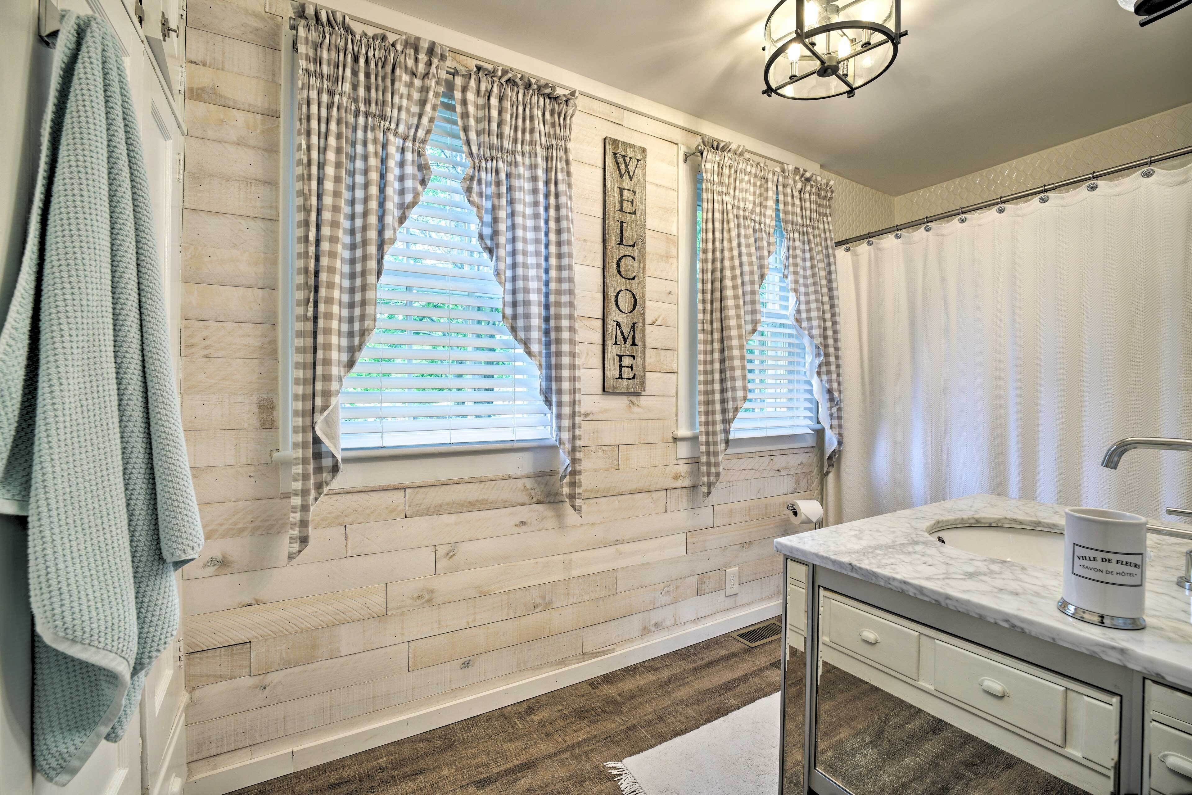 Un bagno con una parete in legno, un lavandino bianco e un asciugamano appeso al muro.