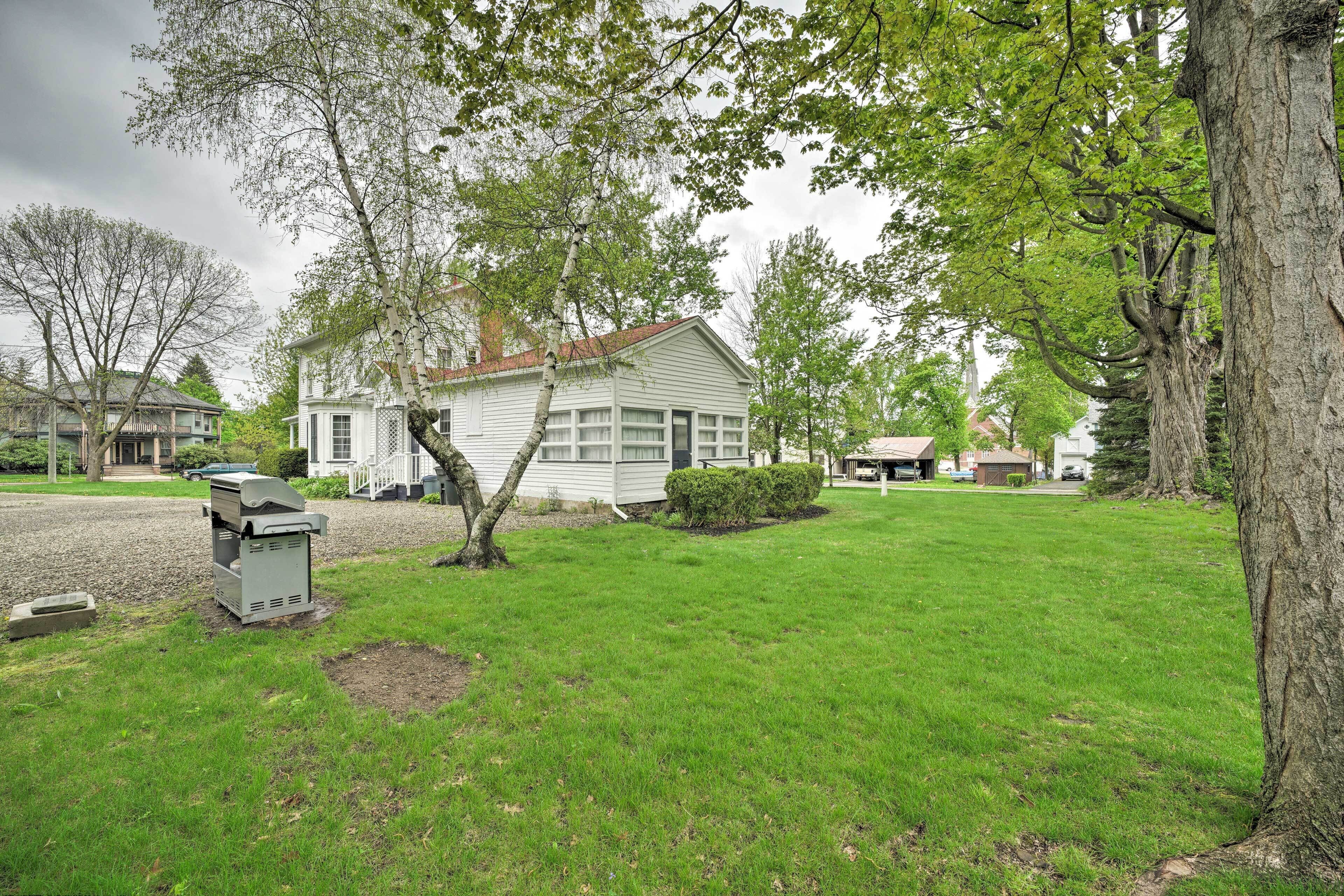 A residential house with a well-maintained lawn, a tree in the foreground, and a driveway leading to the house.