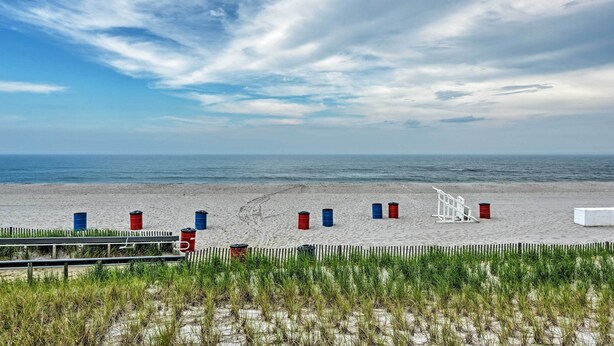A beach with a wooden fence, a white lifeguard stand, and several barrels. - Inviting Seaside Heights Apt < 1 Mi to Beach! (Seaside Heights)