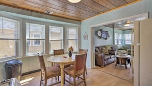 A dining area with a wooden table and chairs, a trash can, and a window with blinds. - Inviting Seaside Heights Apt < 1 Mi to Beach! (Seaside Heights)