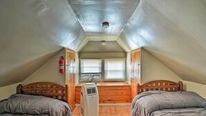 A small attic bedroom with two beds, a heater, and a window with blinds. - Inviting Seaside Heights Apt < 1 Mi to Beach! (Seaside Heights)