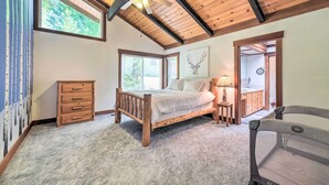 A bedroom with a wooden bed, a ceiling fan, and large windows. - Cabin < Half-mi From Pine Mountain Lake Marina! (Groveland)