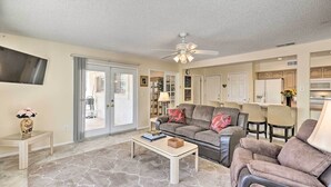 A living room with a sofa, coffee table, and a ceiling fan. There is a sliding glass door leading to a patio. - Quiet Sun City Home w/ Grill - Golf & Hike Nearby! (Sun City)
