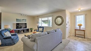 A living room with a grey sectional sofa, a blue armchair, a TV, and a fireplace. - Quiet Sun City Home w/ Grill - Golf & Hike Nearby! (Sun City)