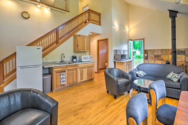 A spacious living area with a wooden staircase, a kitchen with modern appliances, and a cozy seating arrangement.