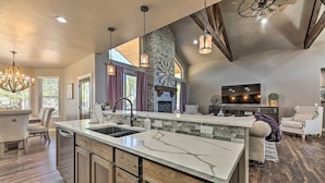 A spacious kitchen with a large island, stone accents, and a fireplace.