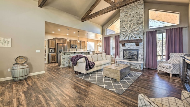 A spacious living room with a fireplace, wooden beams, and a stone accent wall.
