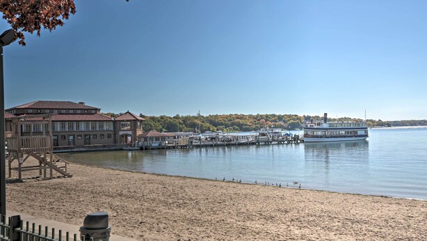 A waterfront hotel with a sandy beach, a dock, and a boat. - Luxe Lake Geneva Retreat in Downtown! (Lake Geneva)