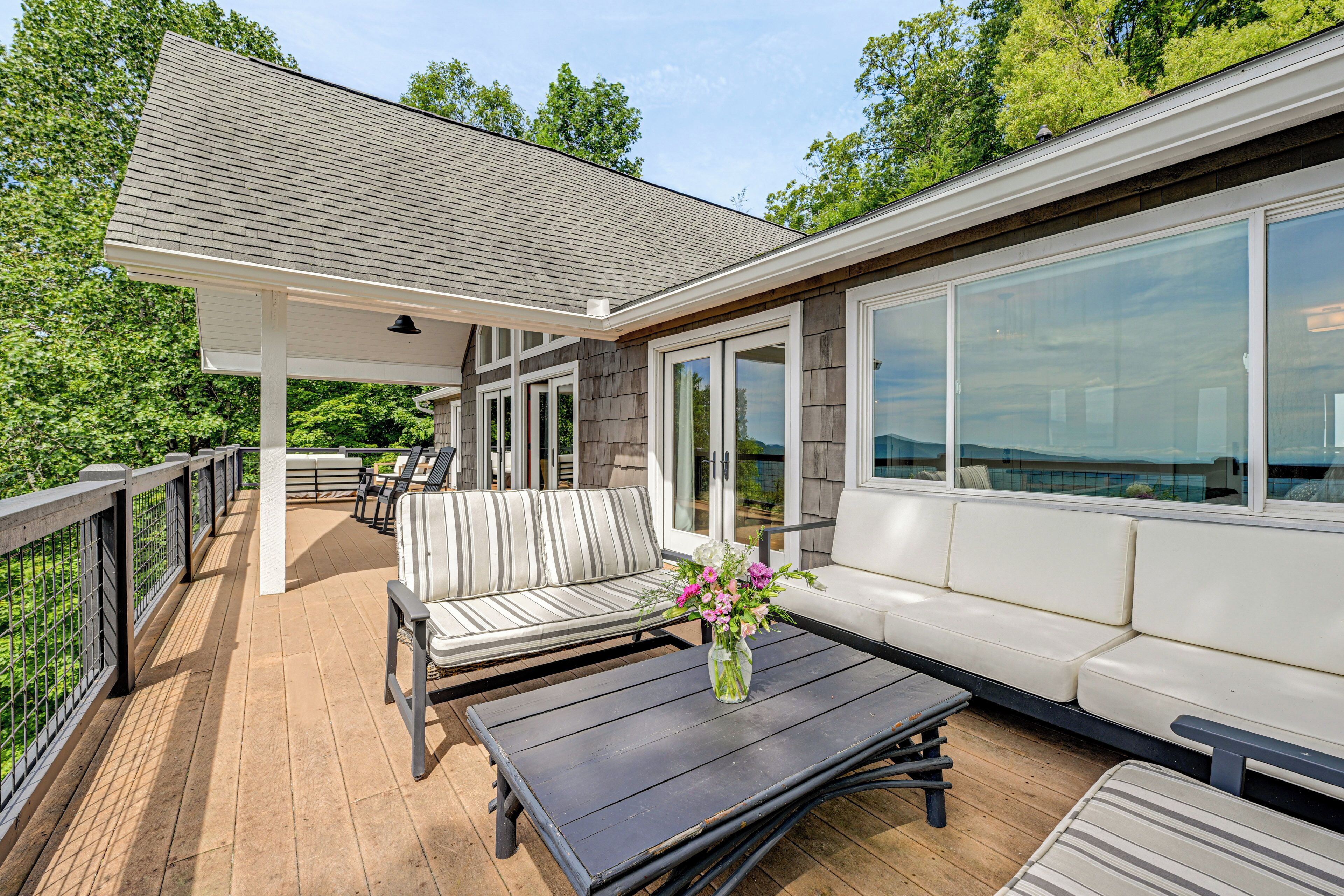 A covered outdoor deck with a sofa, a table, and a potted plant.