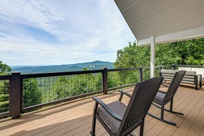 Une terrasse en bois avec deux chaises et une table, offrant une vue sur un paysage montagneux.