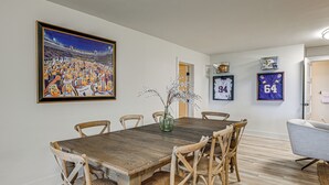 A dining area with a wooden table and chairs, a framed sports painting, and sports memorabilia on the wall. - Ski & Unwind Fireside: Highlands Gem w/ Game Room! (Highlands)