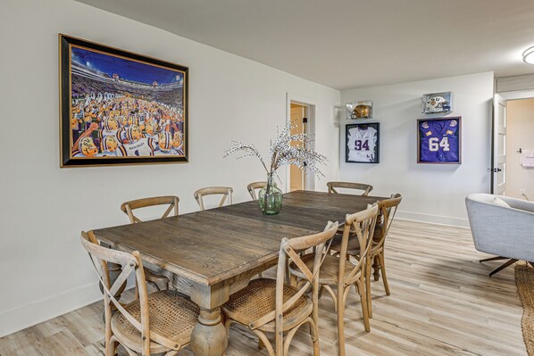A dining area with a wooden table and chairs, a framed sports painting, and sports memorabilia on the wall. - Ski & Unwind Fireside: Highlands Gem w/ Game Room! (Highlands)