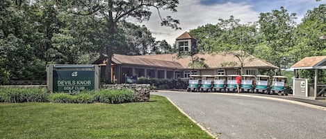 Un club de golf con un letrero, un edificio y carritos de golf.