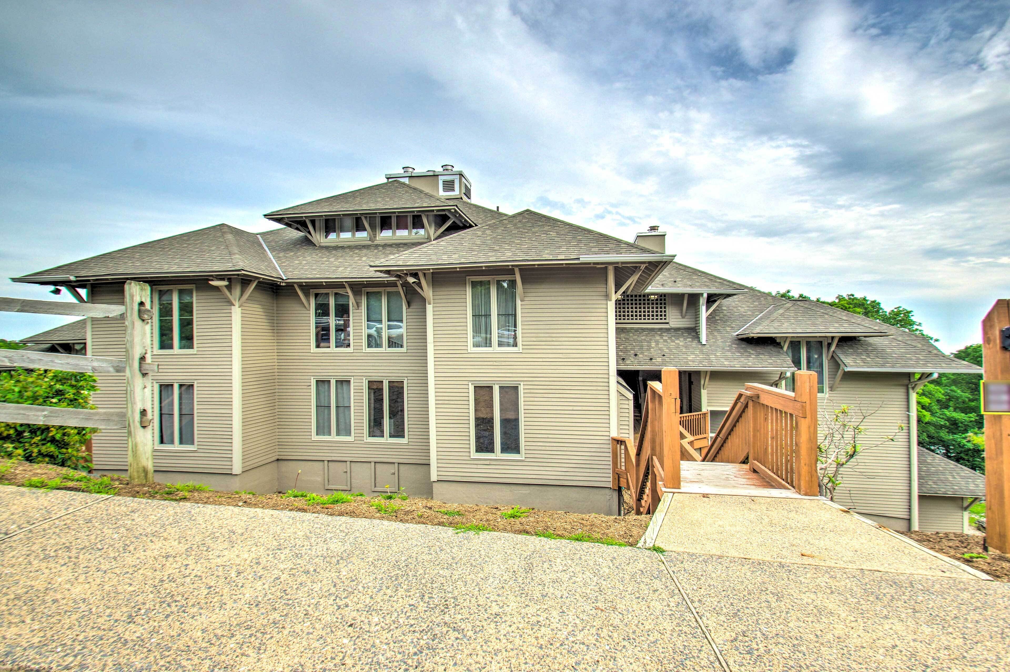 A two-story house with a covered porch and a wooden staircase leading to the entrance.