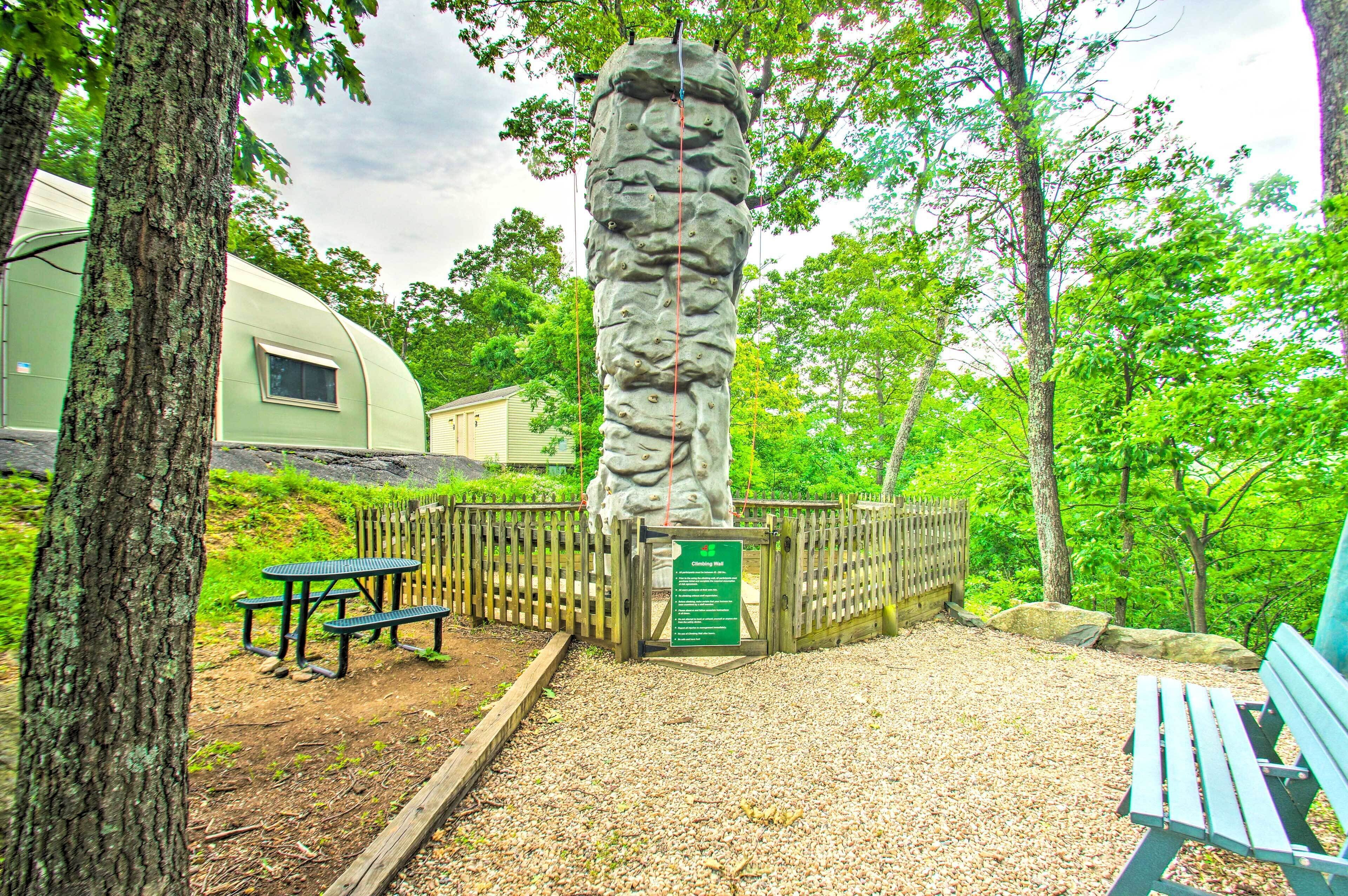A picnic area with benches and a stone monument surrounded by trees.