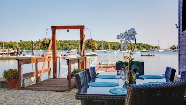 A wooden deck with wicker furniture overlooking a marina.
