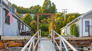A metal bridge leading to a wooden archway in a residential area with stone walls and houses.