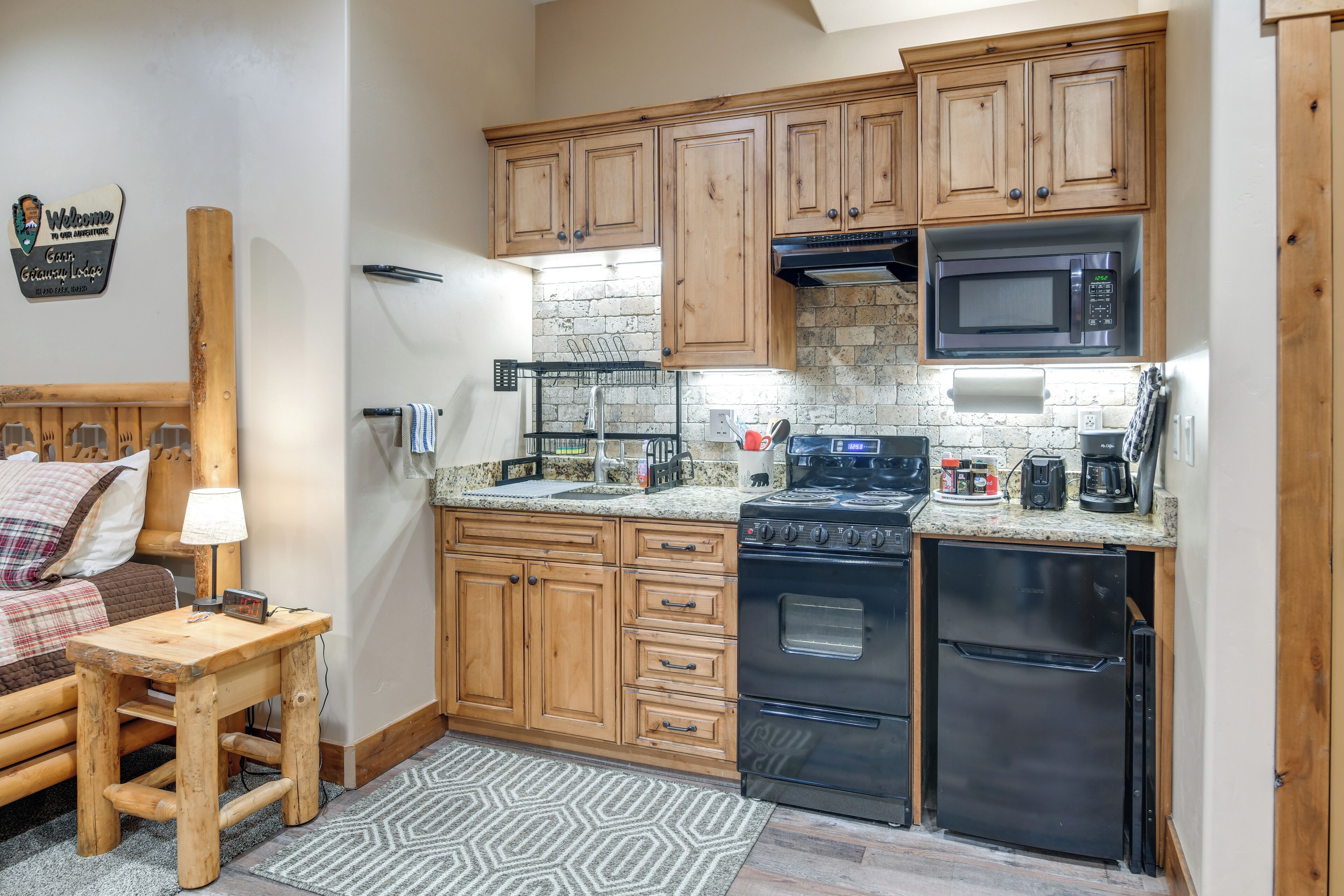 Una cocina compacta con armarios de madera, microondas, estufa y refrigerador.