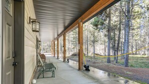 Une véranda couverte avec des poutres en bois, un banc et un sol en béton.