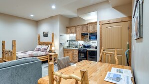 Une pièce de taille modeste comprenant un lit, un canapé, une table à manger en bois et un coin cuisine.