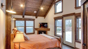 A bedroom with a bed, a fireplace, and large windows. - Dazzling Cle Elum Home; Mountain Views (Cle Elum)