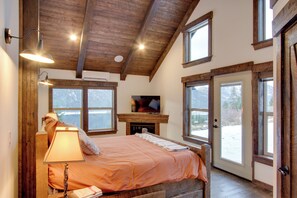 A bedroom with a bed, a fireplace, and large windows. - Dazzling Cle Elum Home; Mountain Views (Cle Elum)