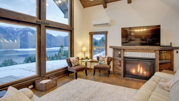 A cozy living room with a fireplace, large windows offering a view of snow-covered mountains, and a comfortable seating area. - Dazzling Cle Elum Home; Mountain Views (Cle Elum)