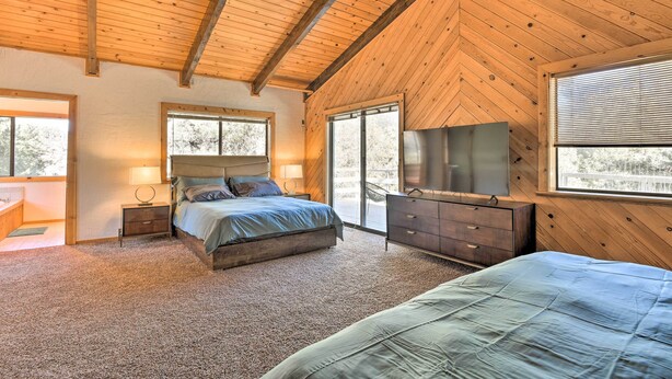 A bedroom with a large bed, a dresser, a TV, and a window. - Luxe Escape w/ Decks, Mtn Views, Game Room! (Pine Mountain Club)