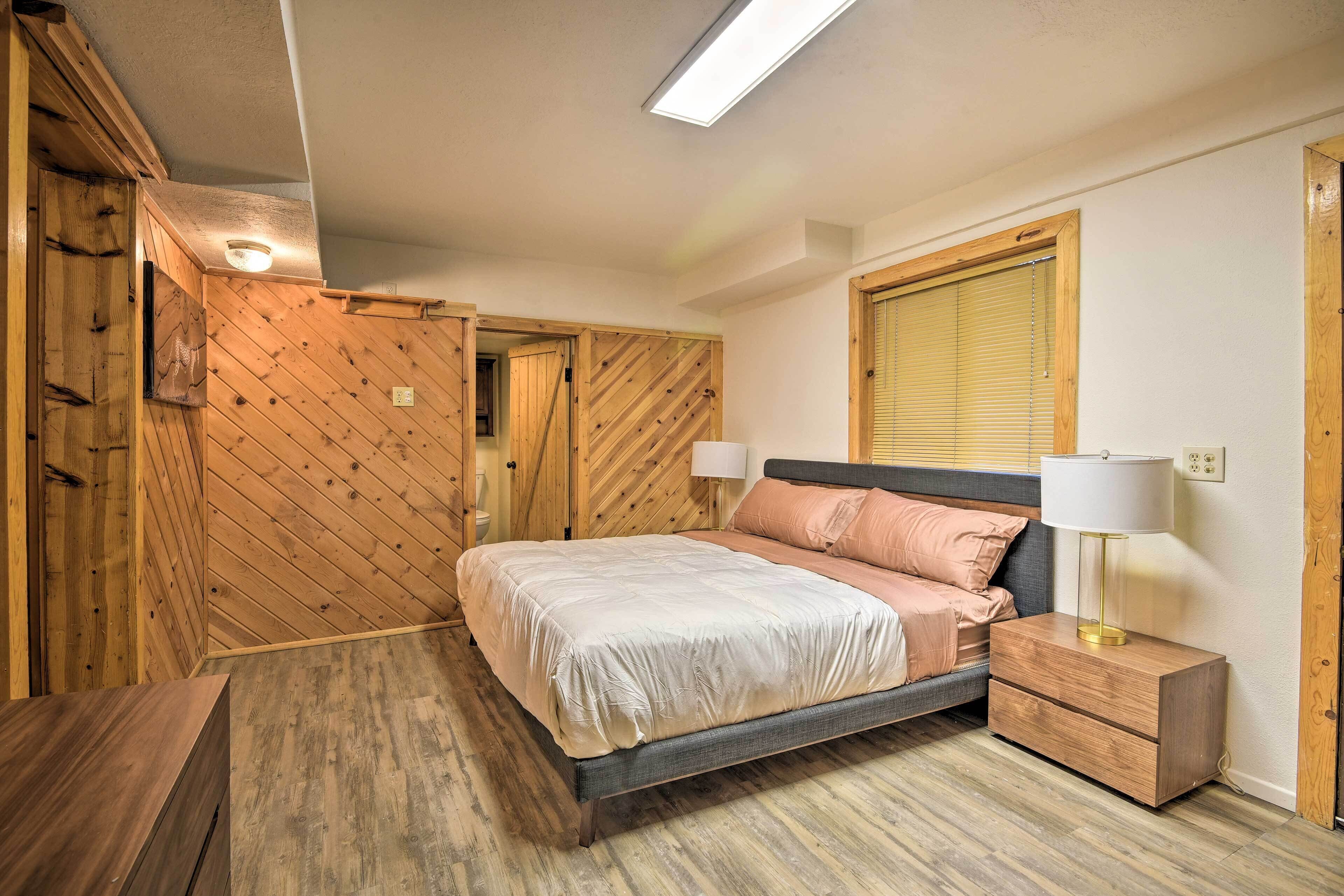 A bedroom with a bed, bedside tables, a window, and wooden walls.