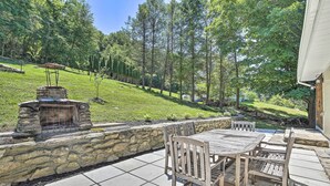 A patio with stone walls, a grill, and wooden furniture.