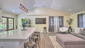 A spacious living area with a large central island, bar stools, a sofa, and a ceiling fan.