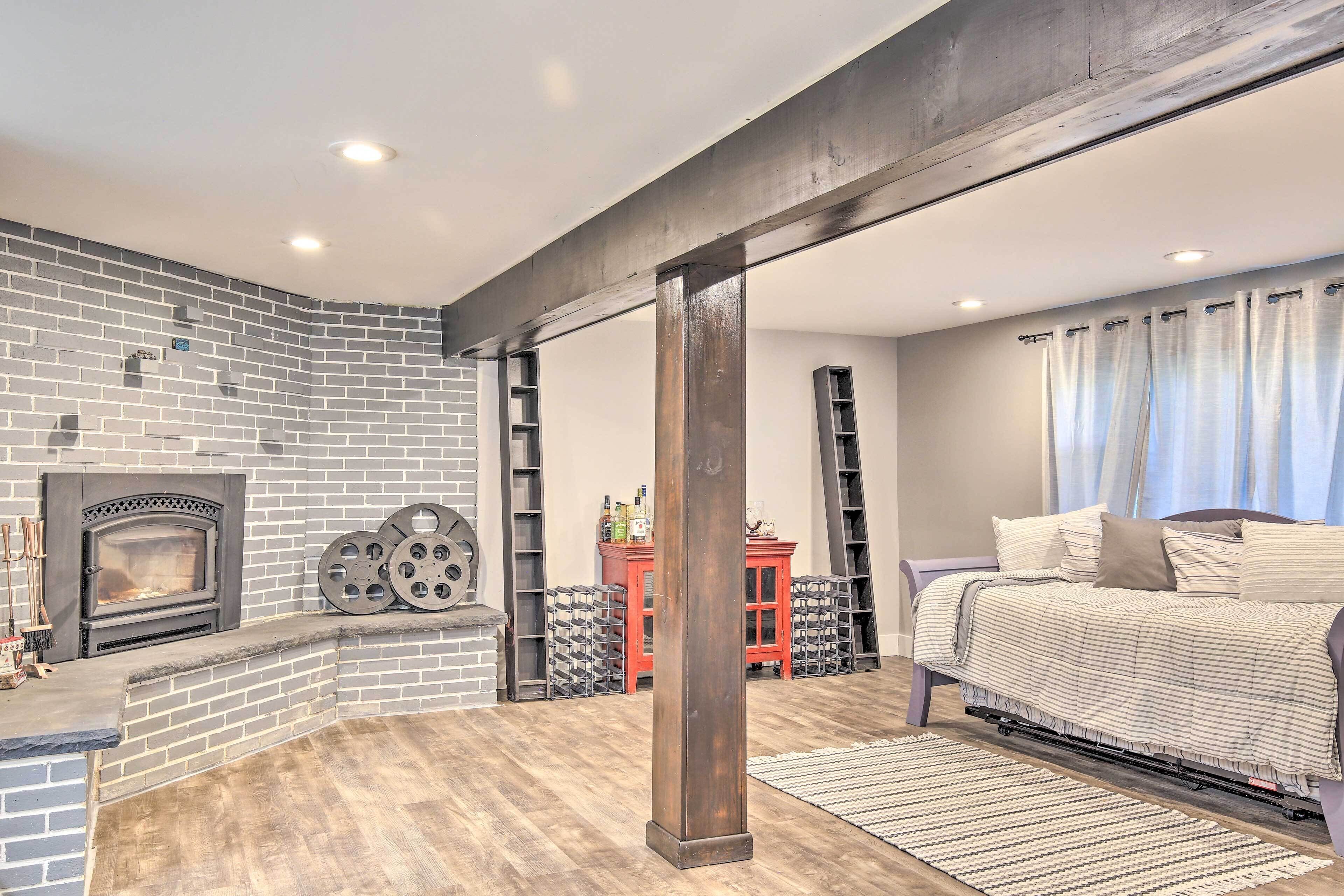 A cozy room with a brick fireplace, a bed with a striped blanket, and a wooden floor.