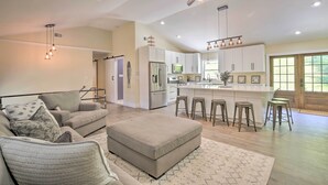 A spacious living room with a sofa, ottoman, and a dining area with stools.