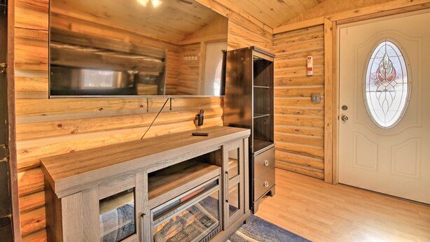Un intérieur en bois avec un téléviseur intégré, un meuble de rangement pour appareils multimédias doté d’une façade en verre et une porte ornée d’un vitrail.