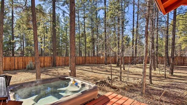 A hot tub on a wooden deck with a wooden fence and trees in the background. - 3-cabin Pinetop Compound w/ Hot Tub & Yard (Pinetop)