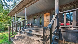 Eine Holzhütte mit einer Veranda, Treppen, die zu einer Tür führen, und Korbmöbeln.