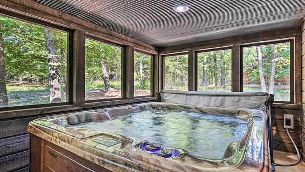 Ein Whirlpool in einem Raum mit großen Fenstern, Holzwänden und einer Decke mit Gittermuster.