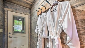 Eine Holzhütte mit Tür, einem Fenster und mehreren weißen Gewändern, die an Haken hängen.