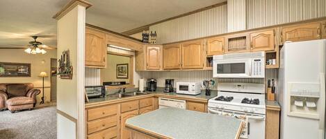 A compact kitchen with wooden cabinets, a microwave, a stove, and a refrigerator.