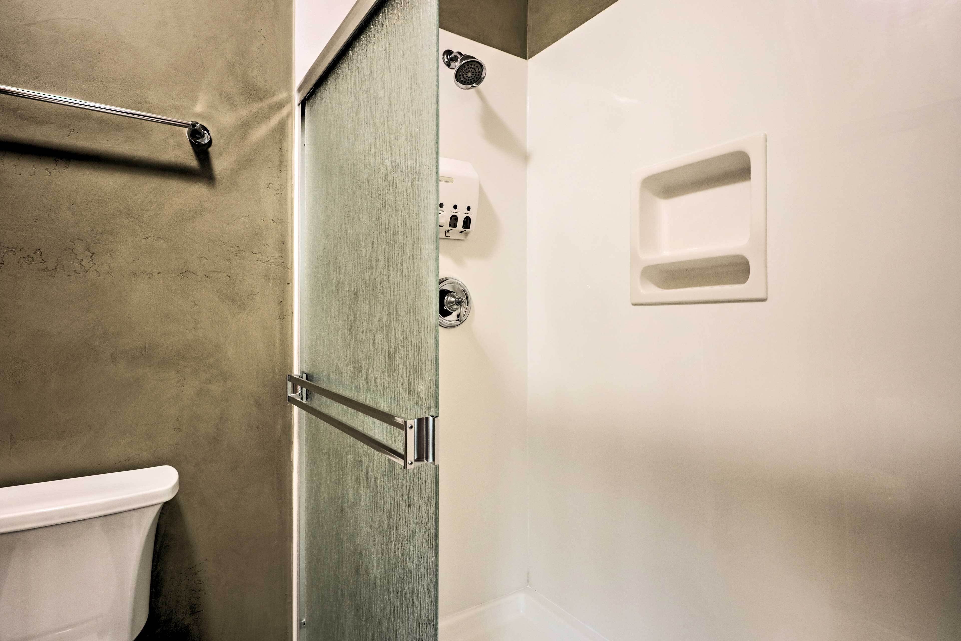 A bathroom with a toilet, a shower area, and a glass door.