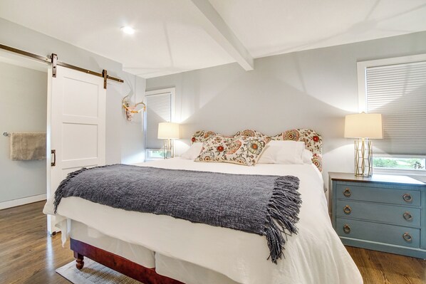 A bedroom with a bed, bedside lamps, a dresser, and a door.