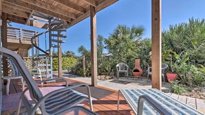 A wooden deck with lounge chairs and a spiral staircase.