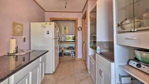 A compact kitchen with white cabinetry, a refrigerator, a stove, and a microwave. There is a wooden door leading to another room.